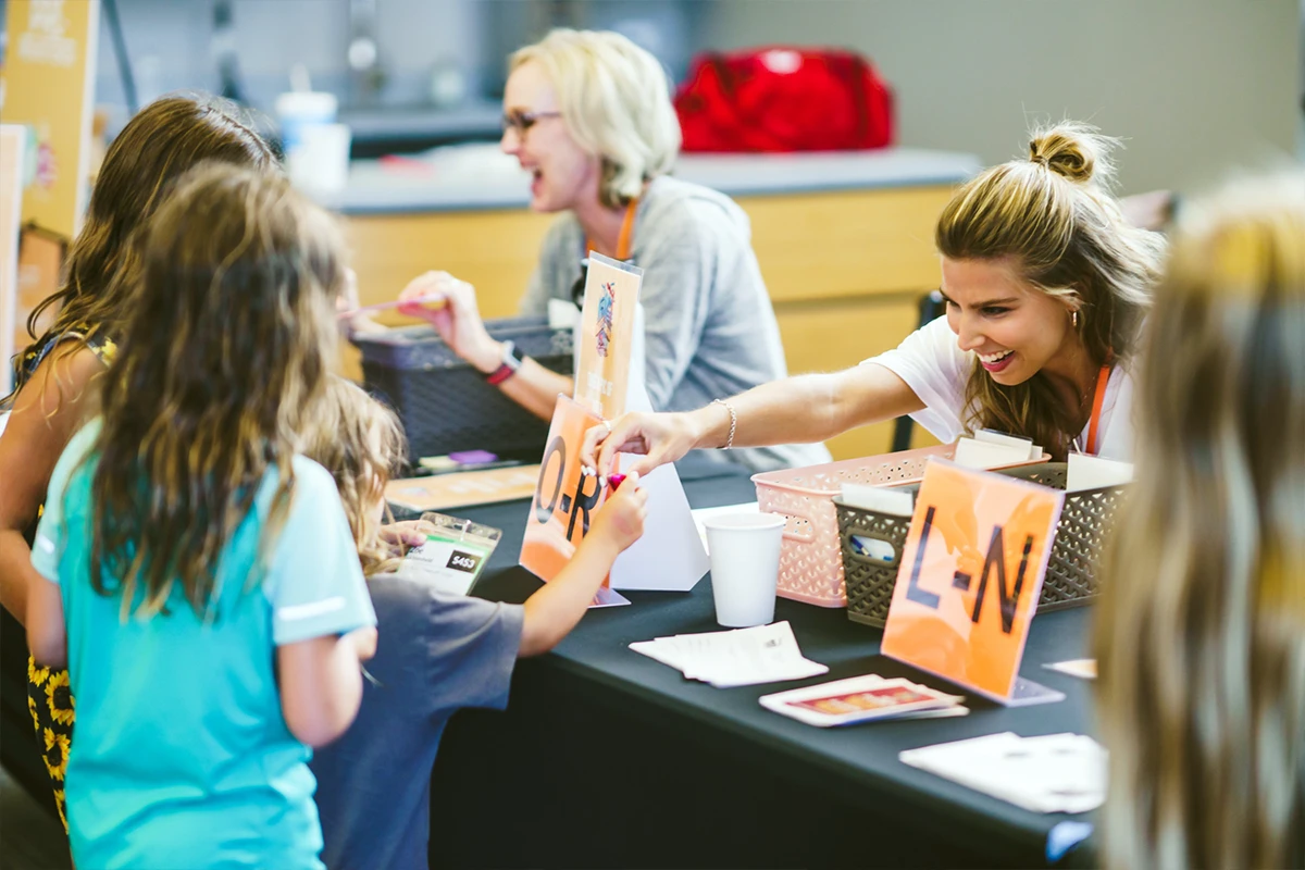 Women helping children at a registration table. Women helping children at a registration table.