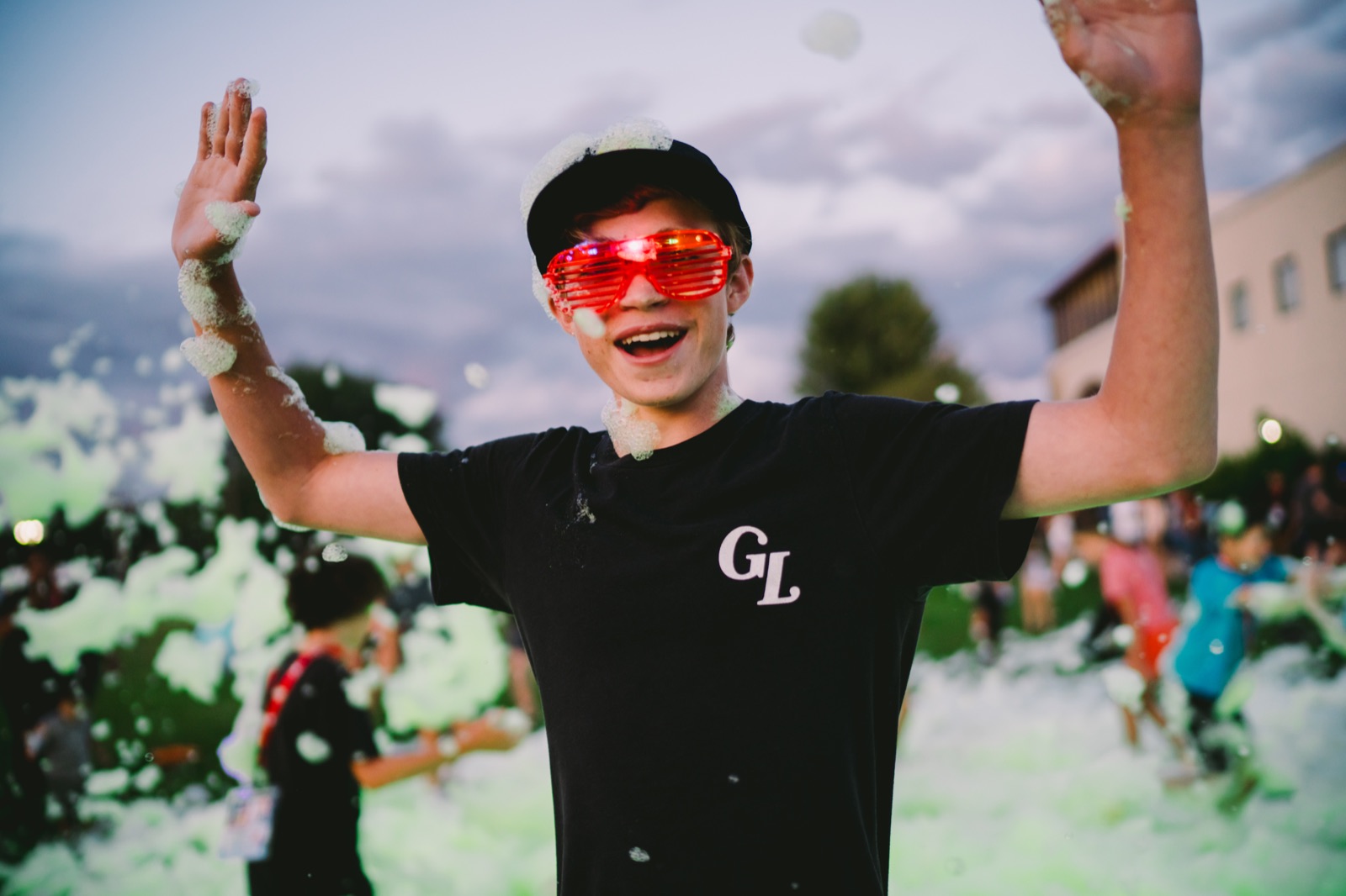 A Gospelife student smiling with arms raised during a foam party at camp