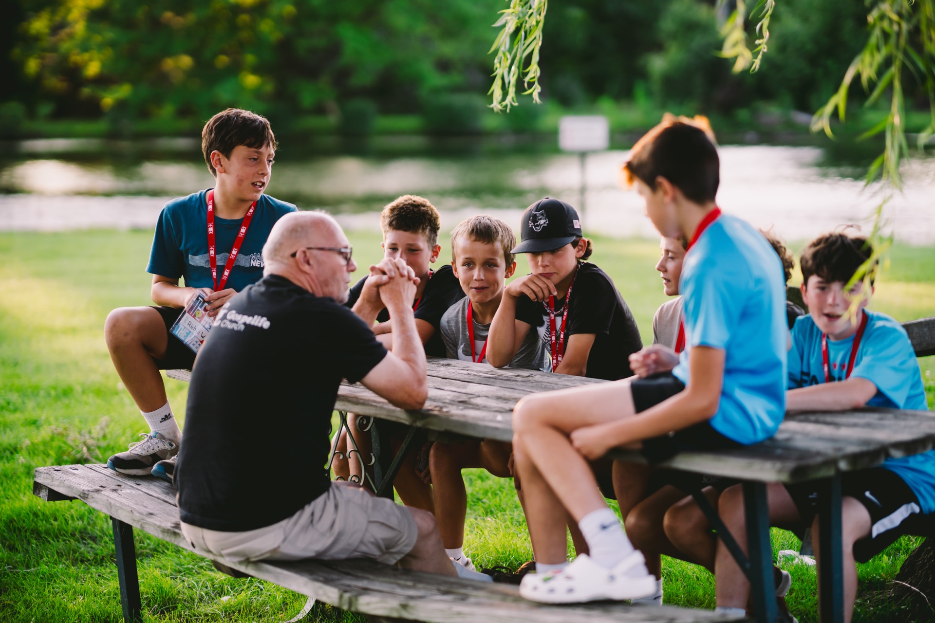 Gospelife Students and a leader sharing a conversation around a picnic table at camp