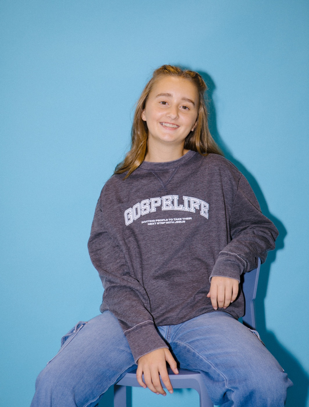 A woman wearing a gray Gospelife crewneck sweatshirt